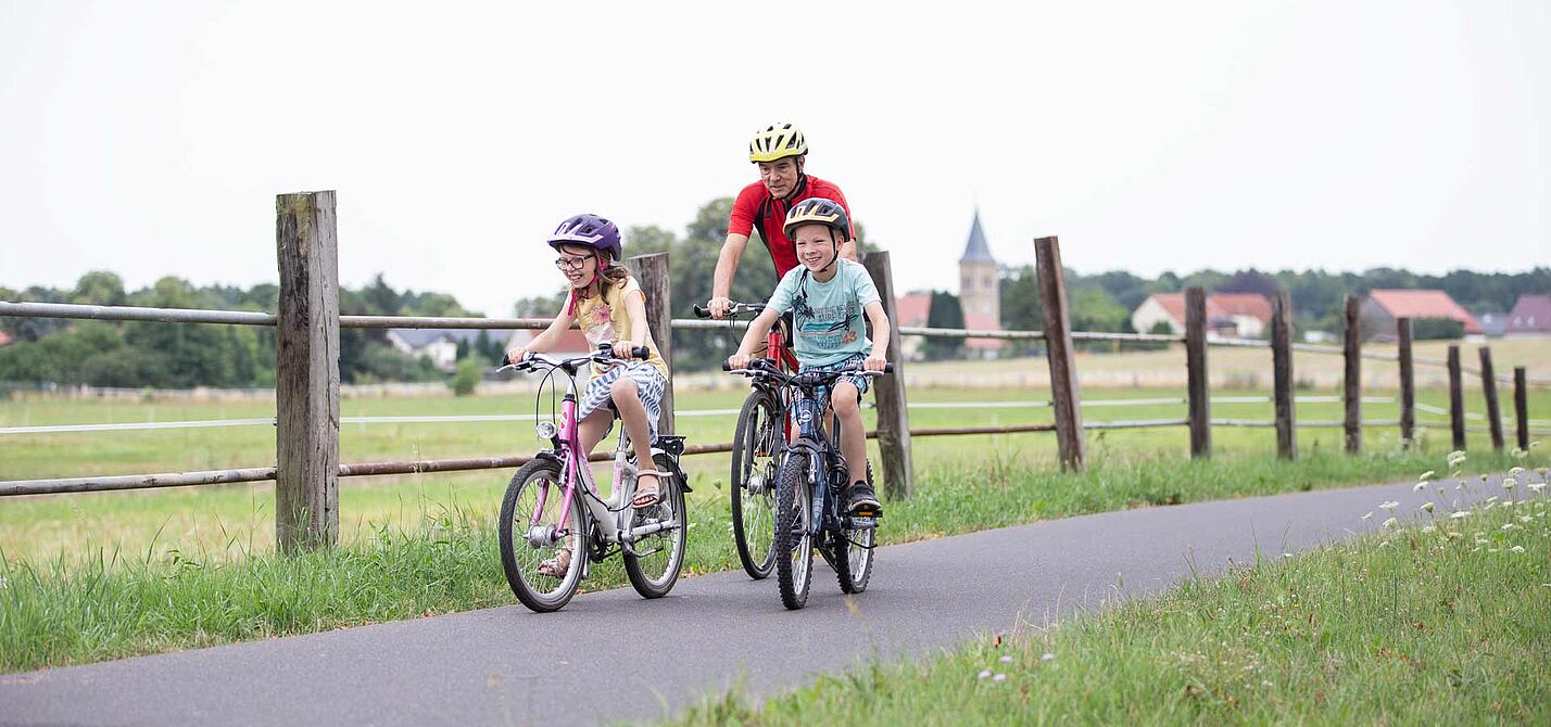 Opa mit Kindern auf Radtour Opa mit zwei Kindern auf Fahrradweg im ländlicher Umgebung